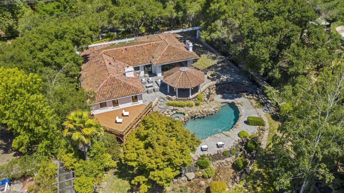 An aerial view of a house with a pool, surrounded by trees.