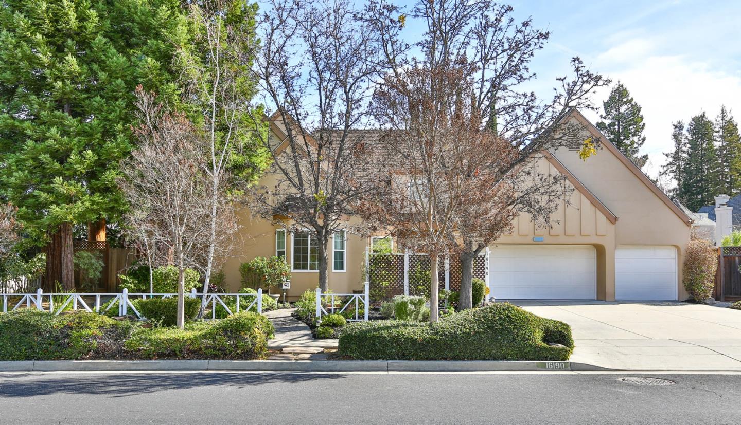 A cream two-story home with pointed roofs.