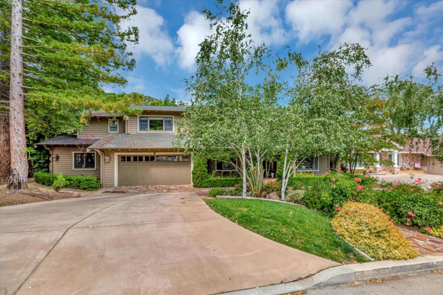 A tan two-story home with a tall birch tree.